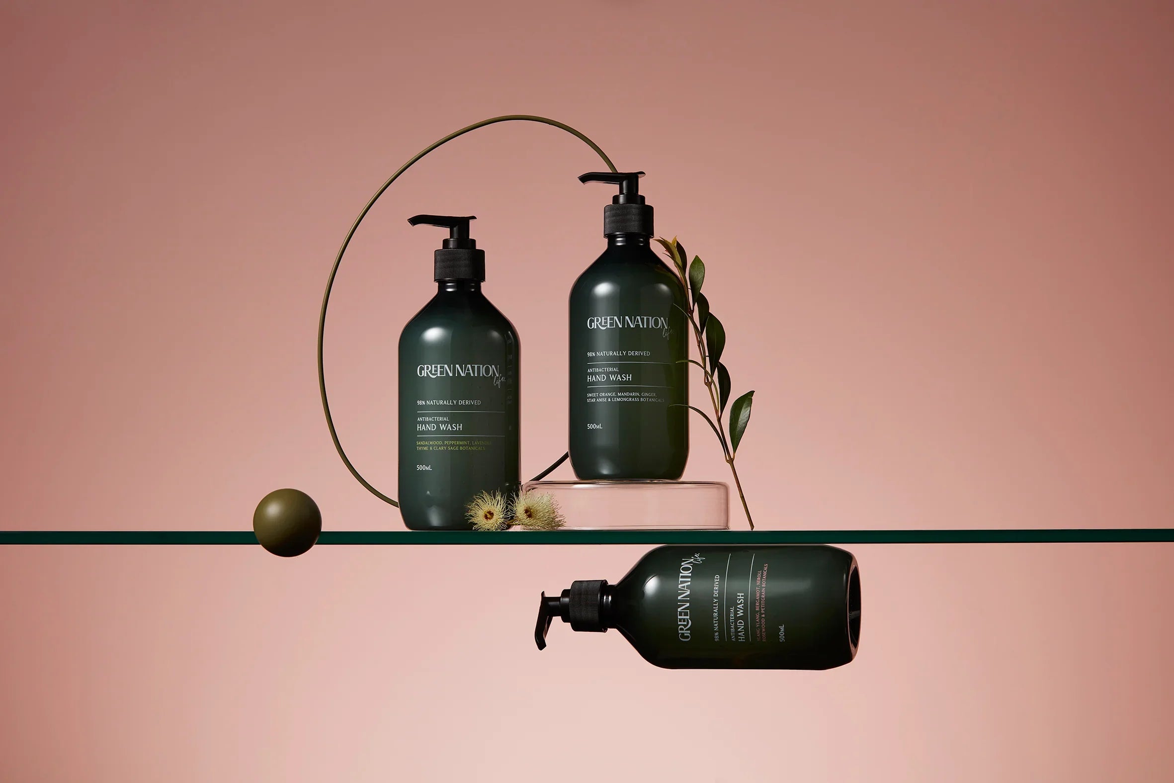 Green Nation antibacterial hand wash bottles with leaves on a minimalist pink background