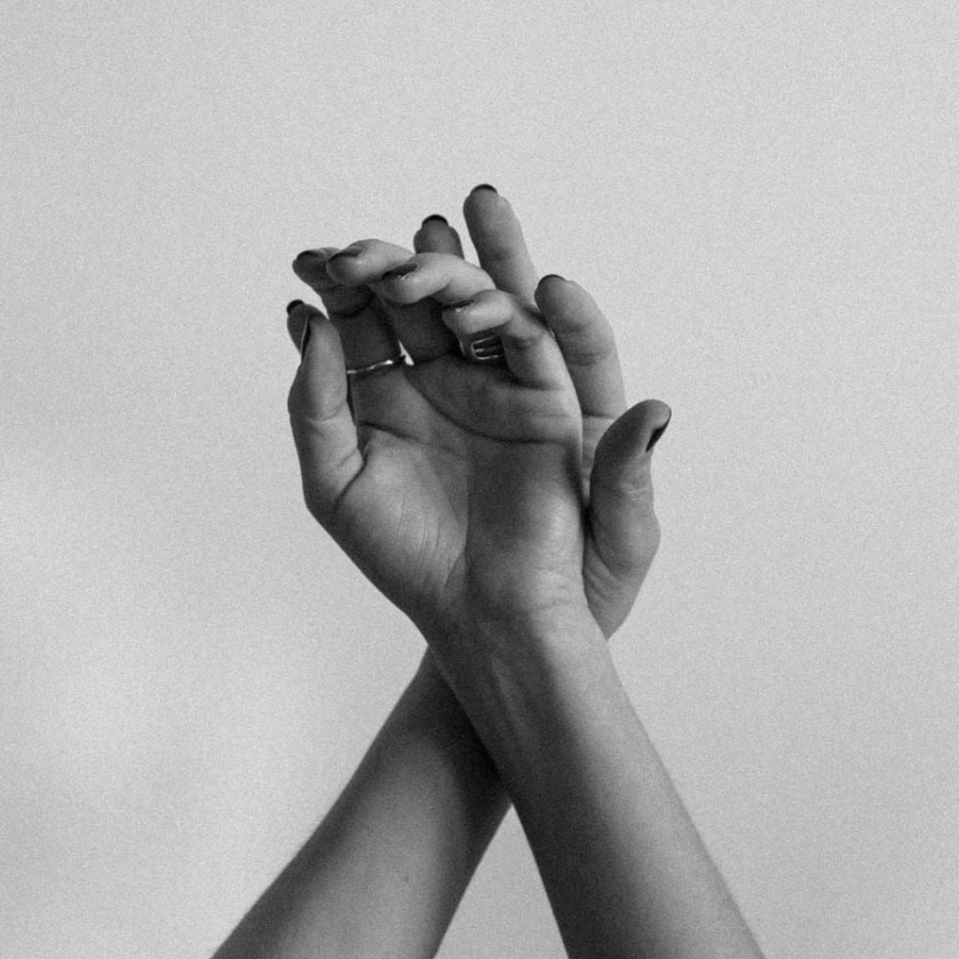 Close-up of two crossed hands with rings, black and white minimal hand care image