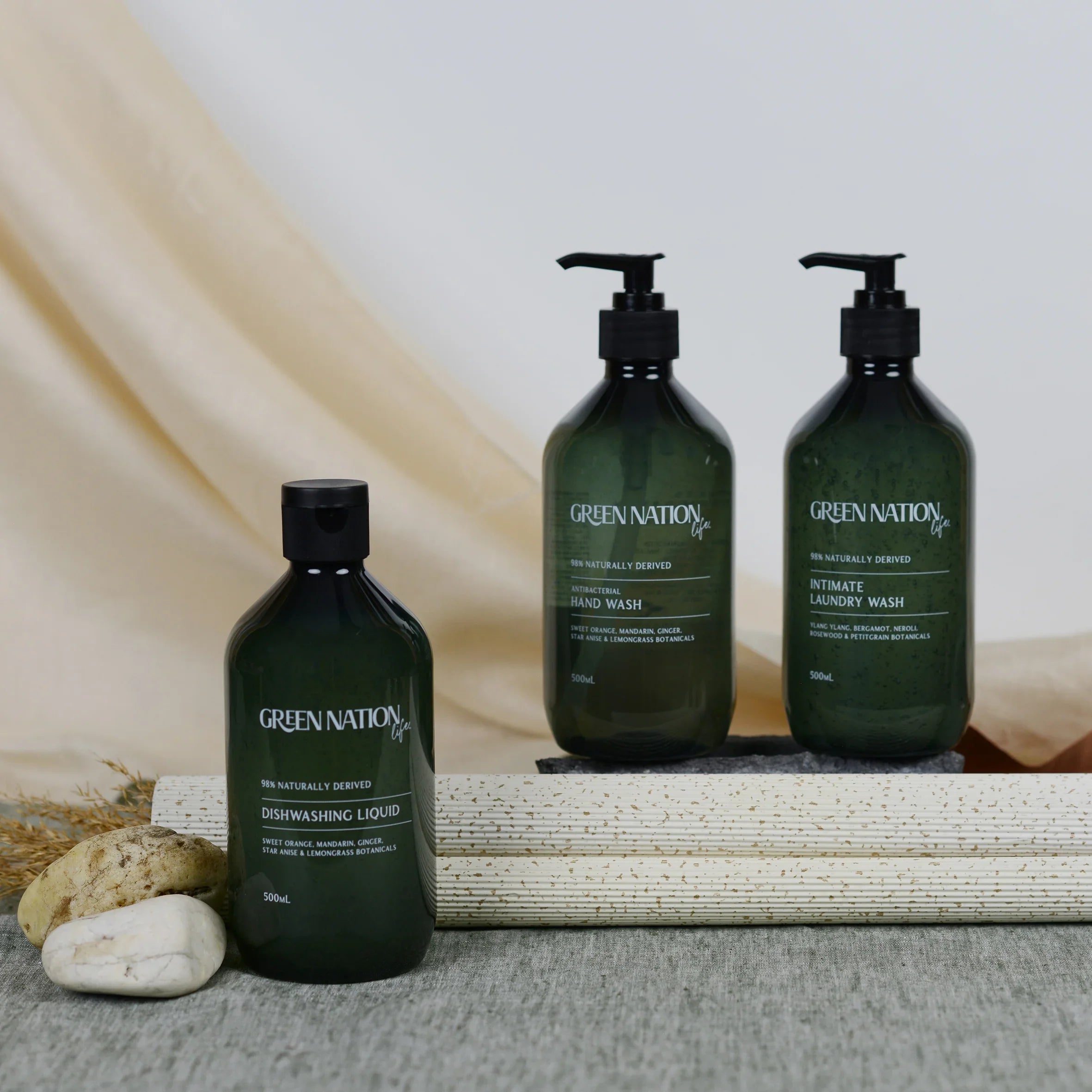 Green Nation Life bottles of dishwashing liquid, hand wash, and laundry wash on display with stones.