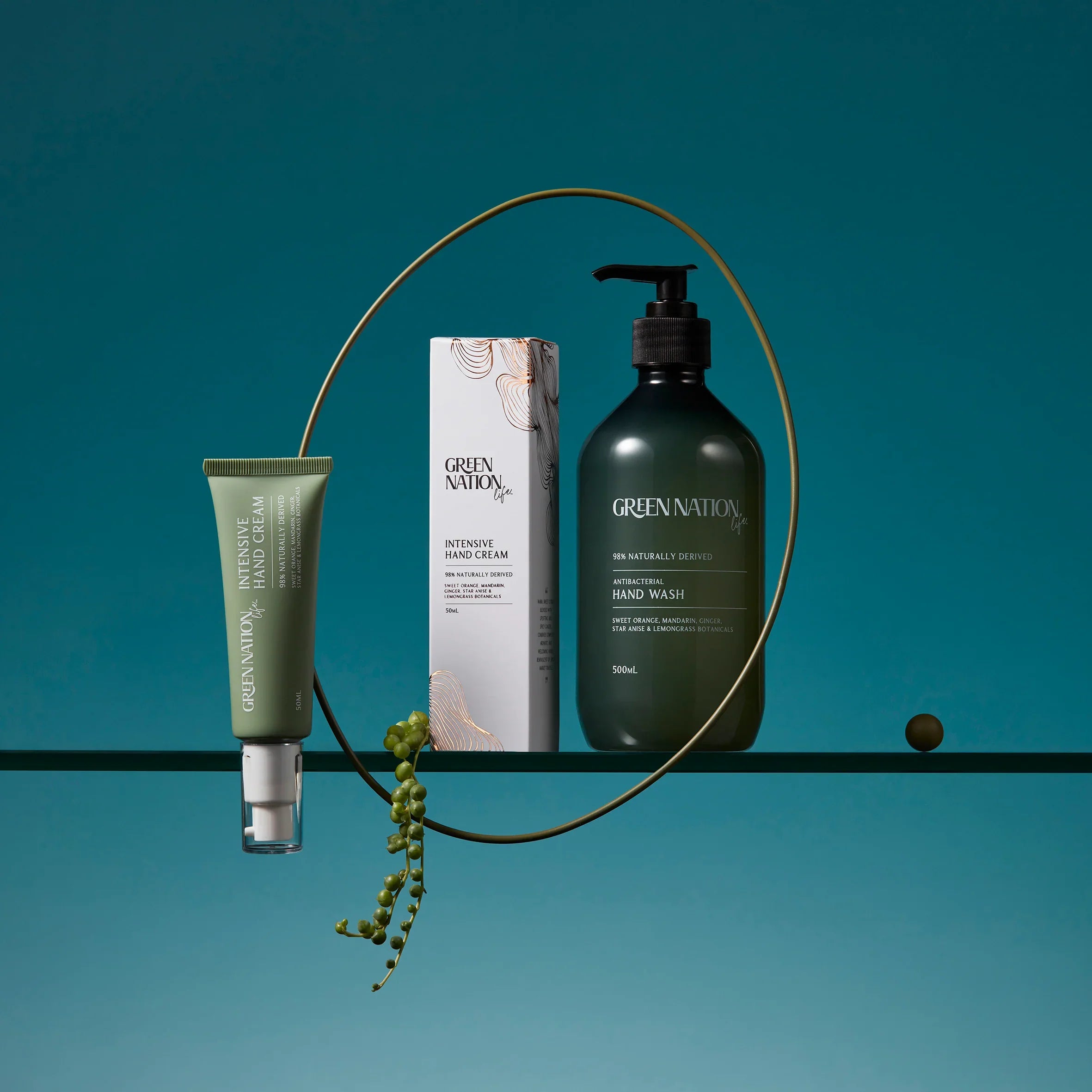 Green Nation antibacterial hand wash and hand cream set on a glass shelf with teal background