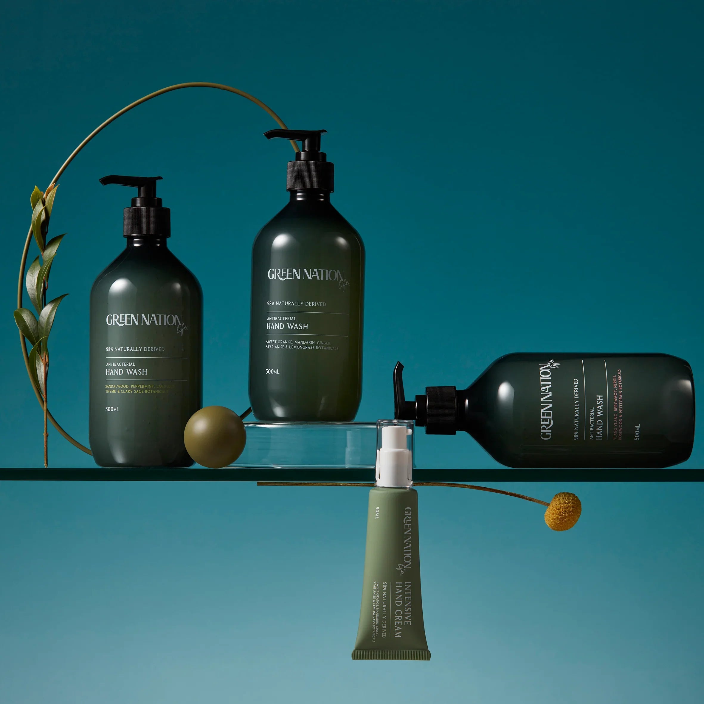 Green Nation Life hand wash bottles and intensive hand cream on a glass shelf with a teal background