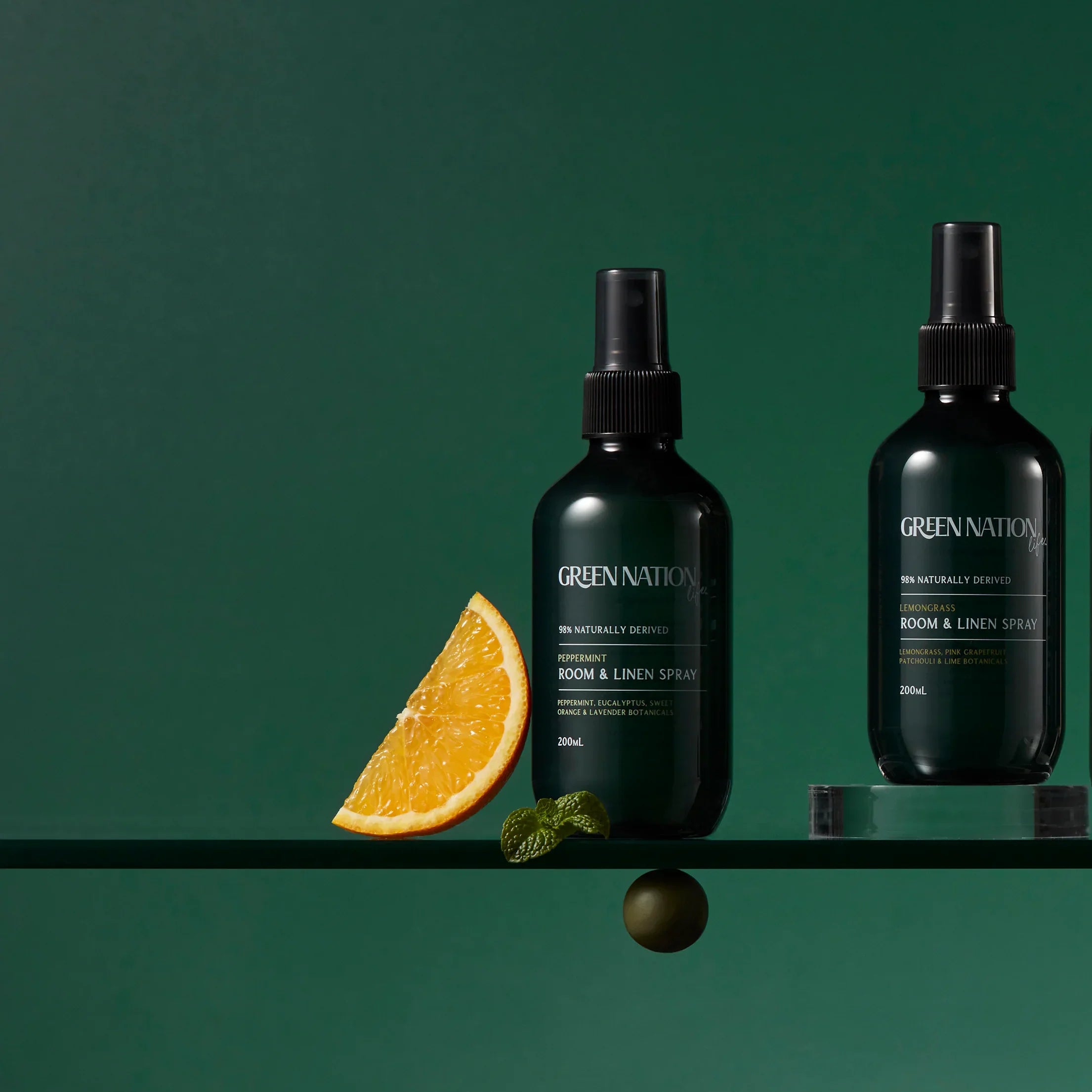 Green Nation Life room and linen spray bottles with orange slice on green background